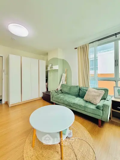 Charming living room with cozy green sofa, modern wardrobe, and natural light from large window.
