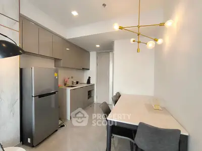 Modern kitchen with sleek cabinetry and dining area, featuring elegant lighting and stainless steel appliances.