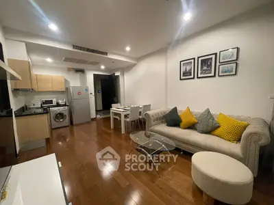 Modern open-plan living room with kitchen, featuring stylish furniture and wooden flooring.
