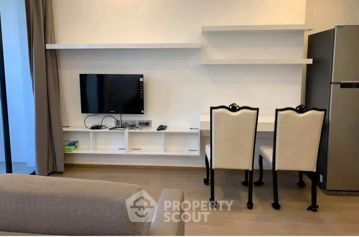 Modern living room with wall-mounted TV, stylish chairs, and sleek shelving.