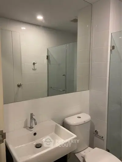 Modern bathroom with sleek fixtures and large mirror in a contemporary apartment.