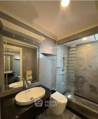 Modern bathroom with sleek design, featuring a glass shower enclosure and stylish fixtures.