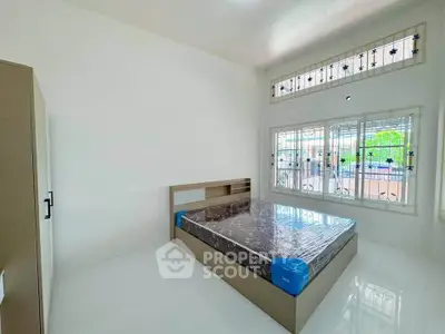 Spacious bedroom with large windows and modern bed in a bright, airy setting.
