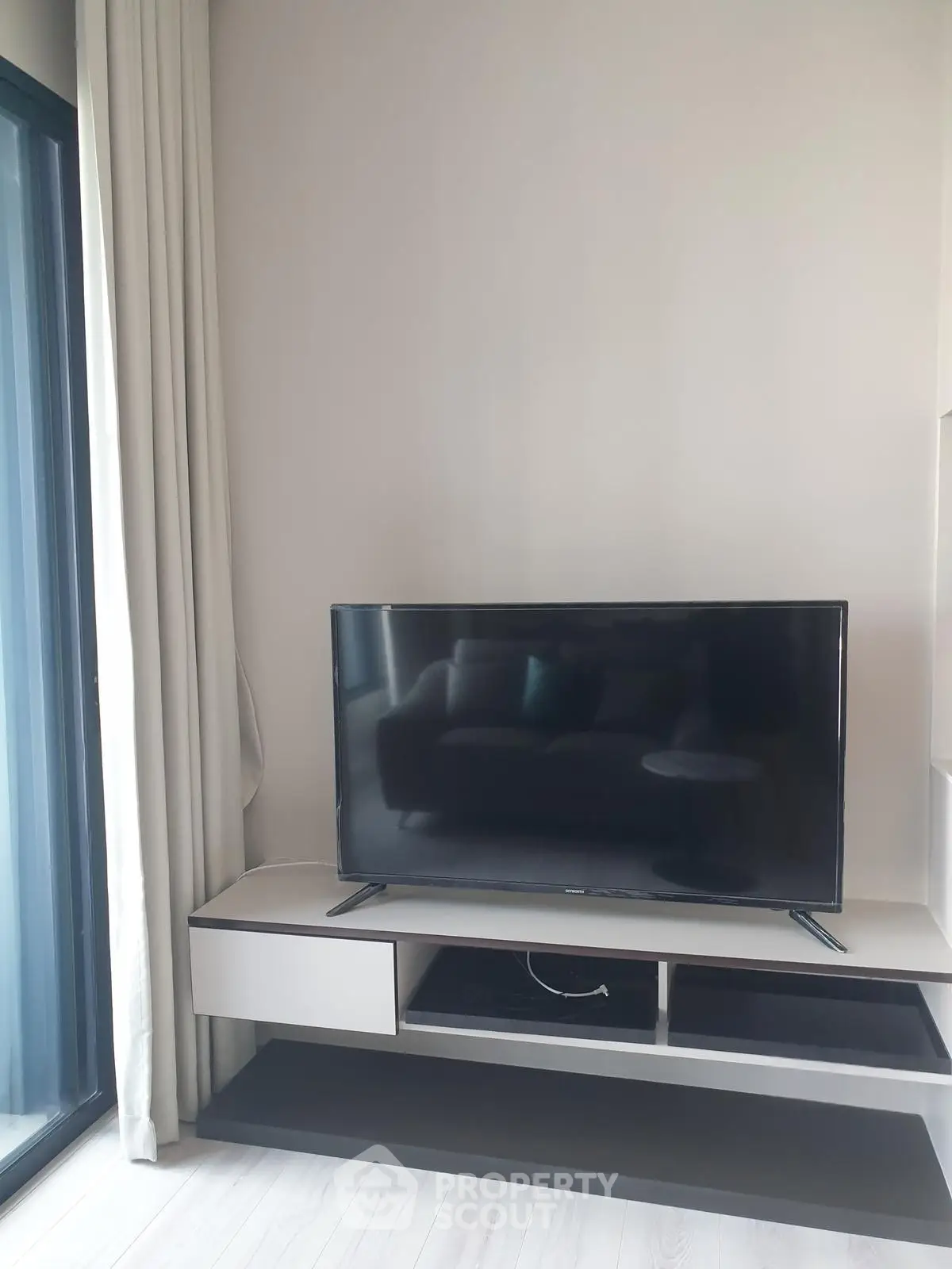 Modern living room with sleek TV setup and large window for natural light.