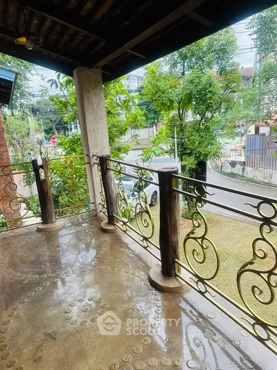 Charming balcony with ornate railing and lush greenery view, perfect for relaxation.