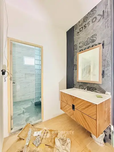 Modern bathroom under renovation with stylish vanity and mirror, showcasing contemporary design elements.