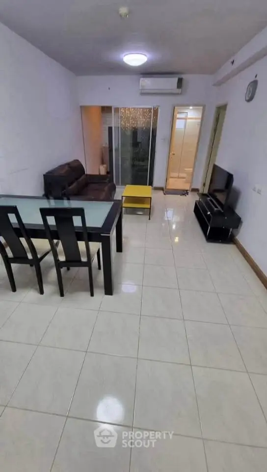 Spacious living room with modern furniture and glass dining table, ideal for family gatherings.