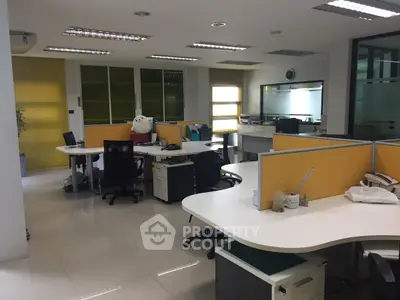Modern office space with sleek design and bright lighting, featuring multiple workstations and large windows.