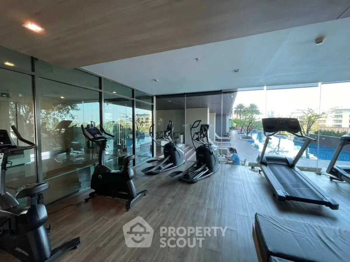 Modern gym with state-of-the-art equipment and pool view in luxury real estate property.