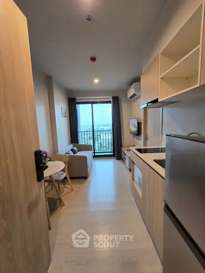 Modern apartment interior with open kitchen and living area, featuring a balcony with a scenic view.
