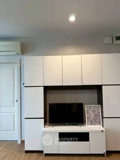 Modern living room with sleek white cabinetry and mounted TV, showcasing minimalist design.