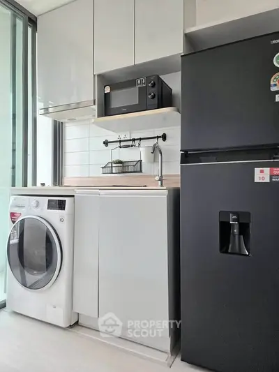 Modern kitchen with sleek appliances including washing machine and fridge, compact yet functional design.