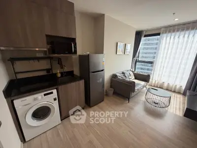 Modern apartment interior with kitchen and living area, featuring washing machine and large window view.
