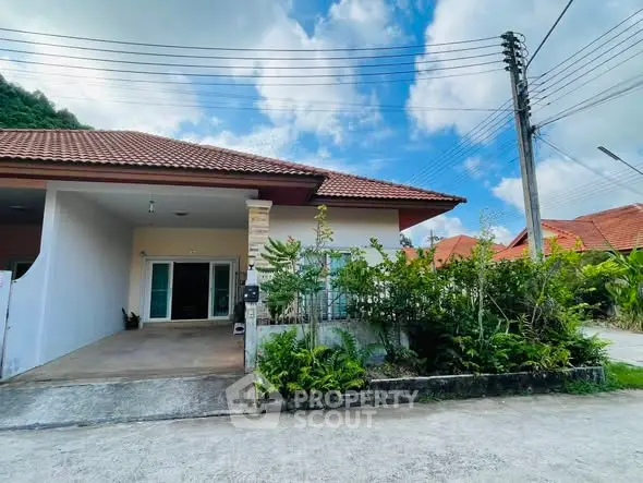 Charming single-story home with red-tiled roof and lush garden in a serene neighborhood.