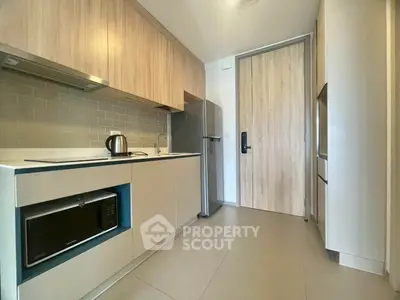Modern kitchen with sleek cabinetry, built-in microwave, and stainless steel fridge in a contemporary apartment.