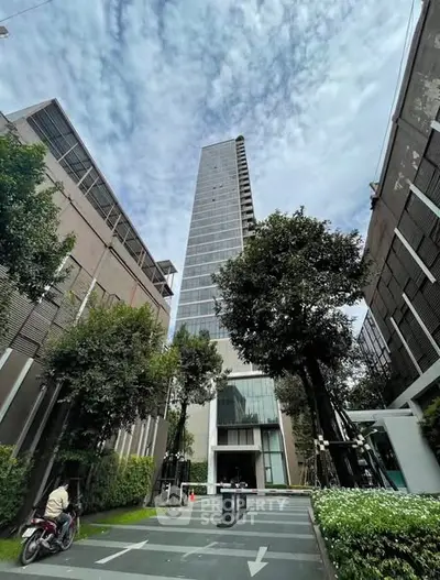 Stunning high-rise building with modern architecture and lush greenery in urban setting.