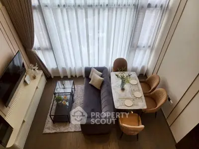 Modern living room with high ceilings, elegant decor, and large windows for natural light.