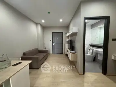 Modern apartment interior with cozy living room and adjacent bathroom, featuring sleek furniture and neutral tones.