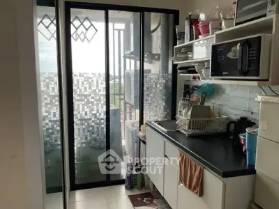 Compact kitchen with sliding glass door leading to balcony, featuring modern appliances and efficient storage.