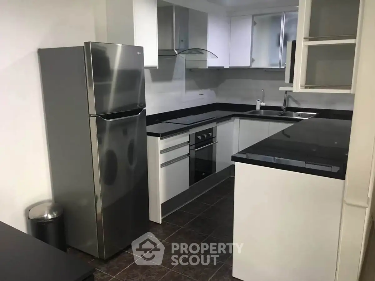 Modern kitchen with sleek black countertops and stainless steel appliances in a contemporary apartment.