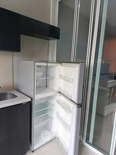 Modern kitchen with sleek open fridge and sliding glass doors, perfect for contemporary living.