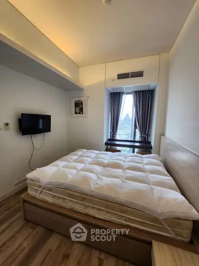 Cozy bedroom with modern decor and large window offering city views, perfect for relaxation and comfort.