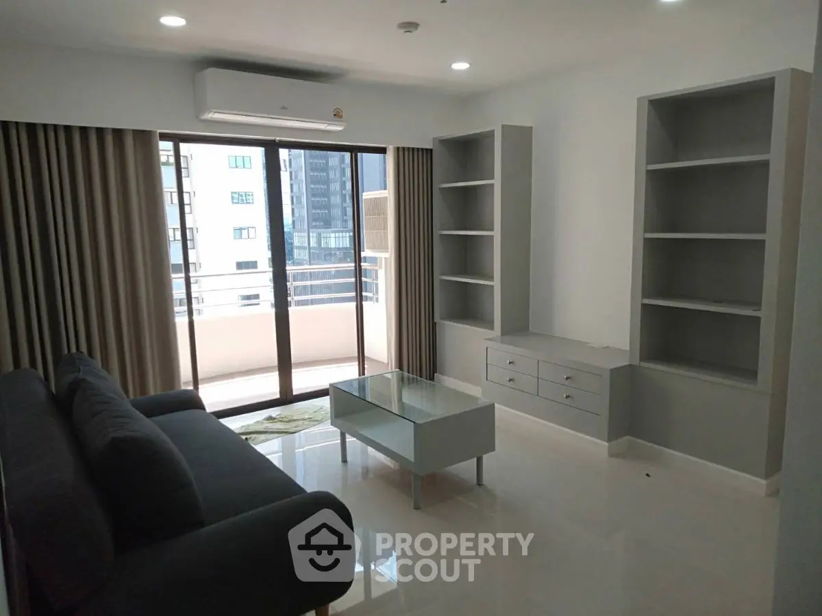 Modern living room with sleek furniture and large windows offering city views.