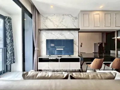 Modern living room with marble accent wall and sleek furniture, featuring a large TV and stylish decor.