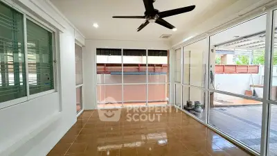 Spacious sunlit room with large windows and ceiling fan, perfect for versatile living space.