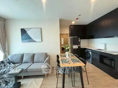 Modern open-layout kitchen and living room with sleek black cabinetry and cozy seating area.