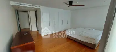 Spacious bedroom with wooden flooring and modern ceiling fan in a minimalist design.