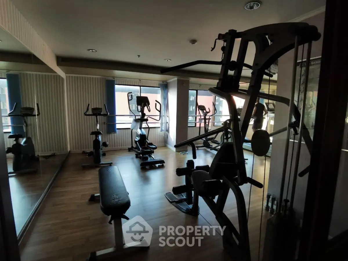 Spacious gym with modern fitness equipment and large mirrors in a well-lit room.