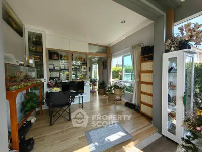 Spacious living room with wooden flooring and large windows offering natural light.