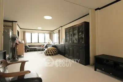 Spacious living room with elegant dark wood furniture and large windows for natural light.