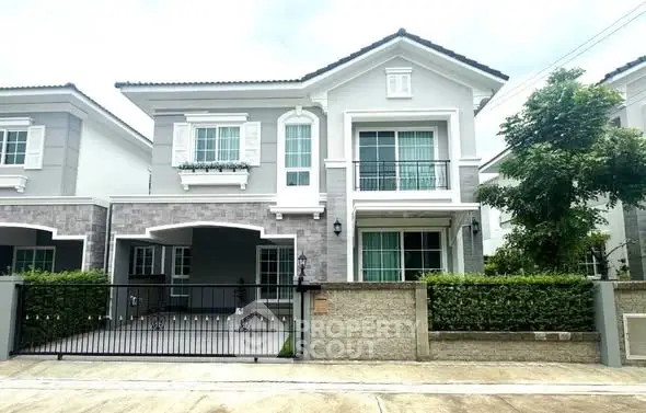 Charming two-story house with modern facade and gated driveway in suburban neighborhood.