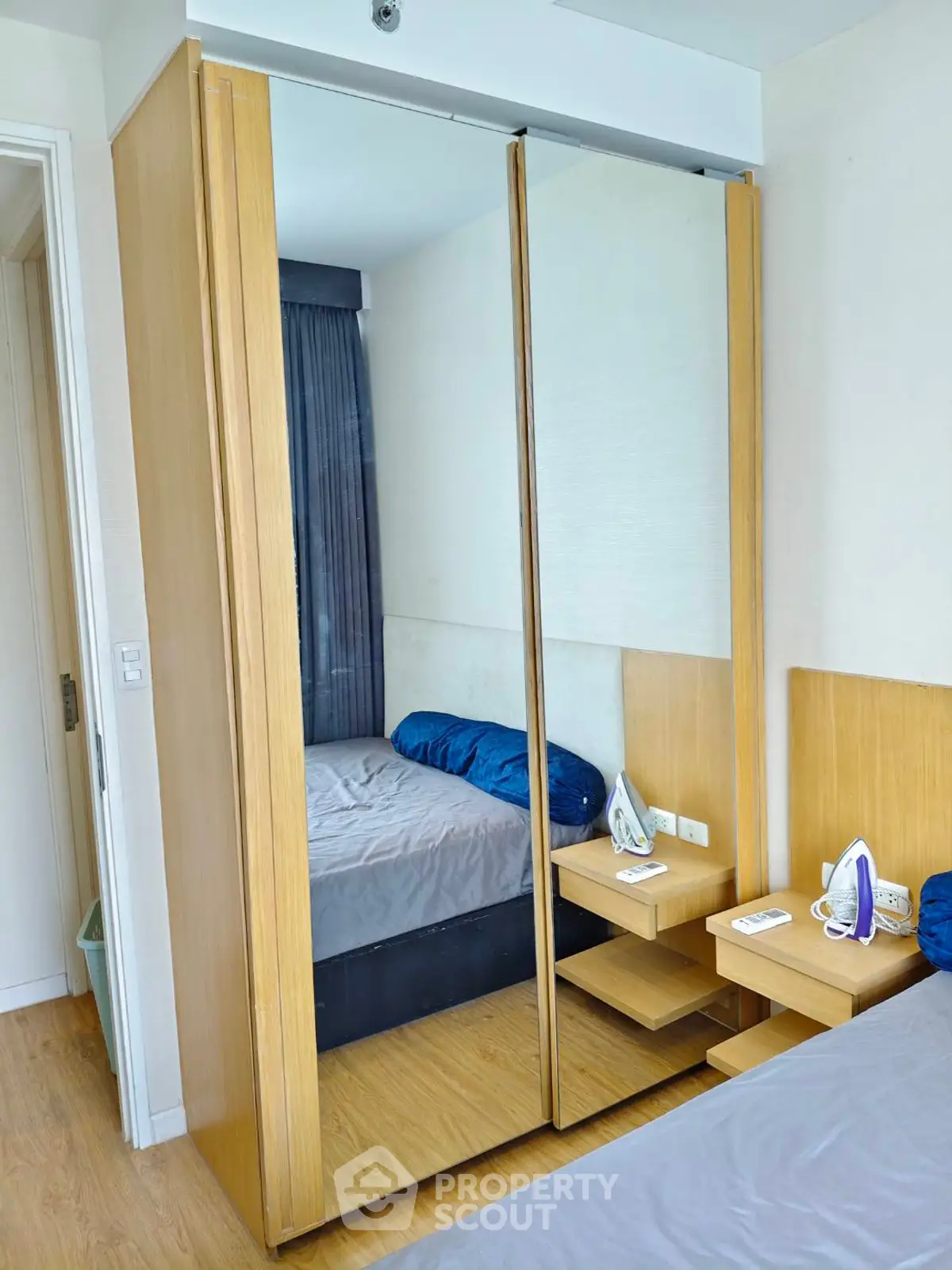 Modern bedroom with mirrored wardrobe and wooden flooring, featuring a cozy bed and sleek design.