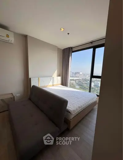 Modern bedroom with city view, featuring a cozy bed and stylish sofa.