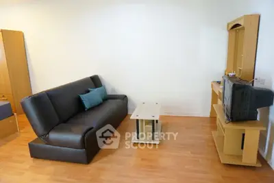 Cozy living room with black sofa and wooden TV stand, perfect for relaxation.