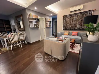 Cozy and inviting living room with warm wooden floors, comfortable seating, and a well-organized bookshelf, perfect for relaxation and entertainment.