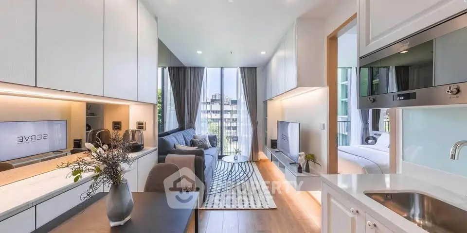 Modern open-plan living room with sleek kitchen and cozy bedroom view, featuring elegant decor and natural light.
