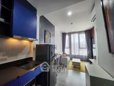 Modern open-plan kitchen and living room with stylish blue cabinets and cozy seating area.