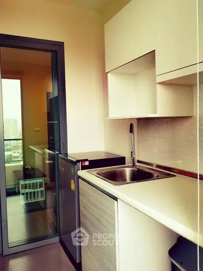 Modern compact kitchen with sleek design and city view balcony access.