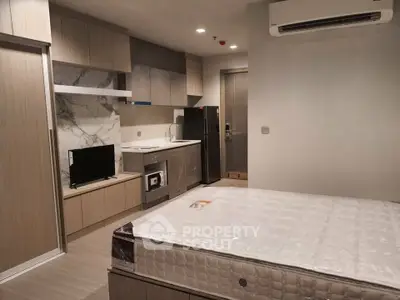 Modern studio apartment with sleek kitchen and cozy living area, featuring a comfortable bed and stylish decor.