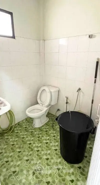 Compact bathroom with tiled walls and green patterned floor