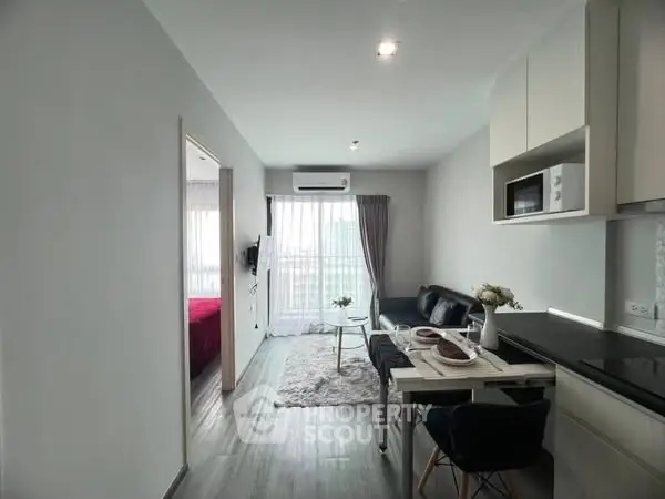 Modern open-plan living room with kitchen, featuring sleek design and natural light.