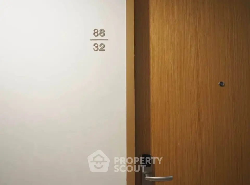 Modern apartment door with sleek wooden finish and room number displayed, showcasing contemporary design.