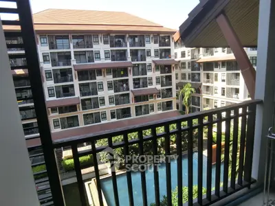 Charming condo balcony view overlooking lush garden and pool in modern residential complex.
