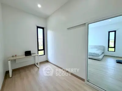 Spacious minimalist bedroom with large windows and wooden flooring