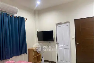 Cozy bedroom with wall-mounted TV and air conditioning, featuring blue curtains and modern decor.