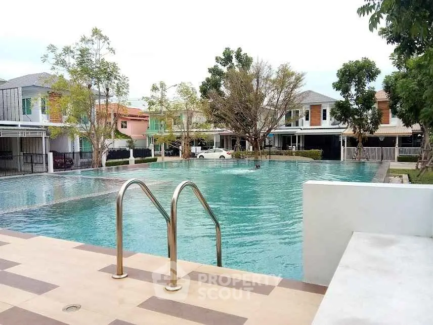 Luxurious residential pool with modern homes in the background, perfect for relaxation.